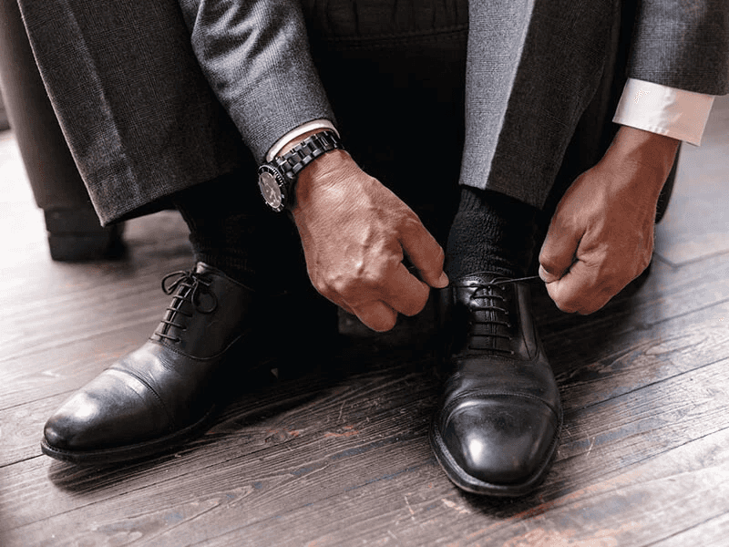 man putting on nice black leather shoes